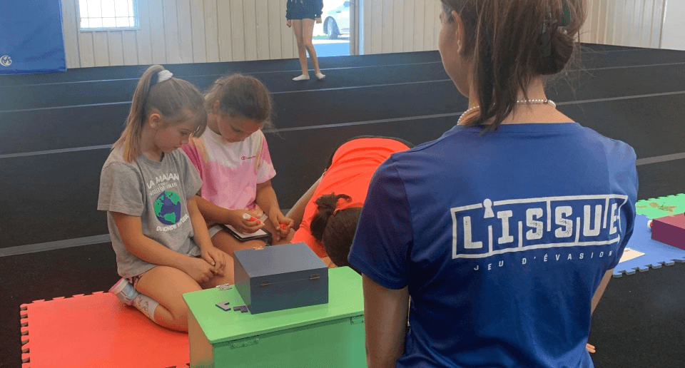 3 enfants en résolution d'énigmes avec la boite mystère en supervision d'un agent l'Isssue.